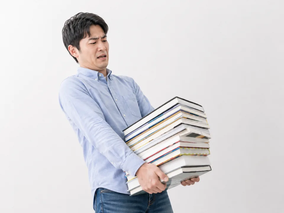 大量の本を抱えて困っている男性