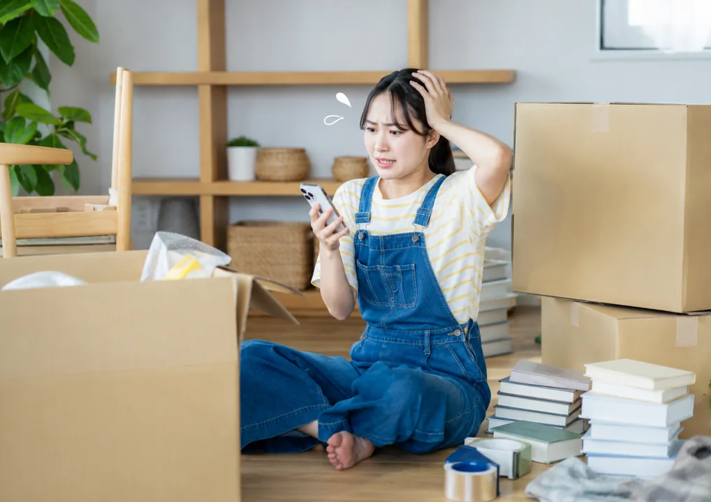 引越しの荷造りで本の片付けに困る女性